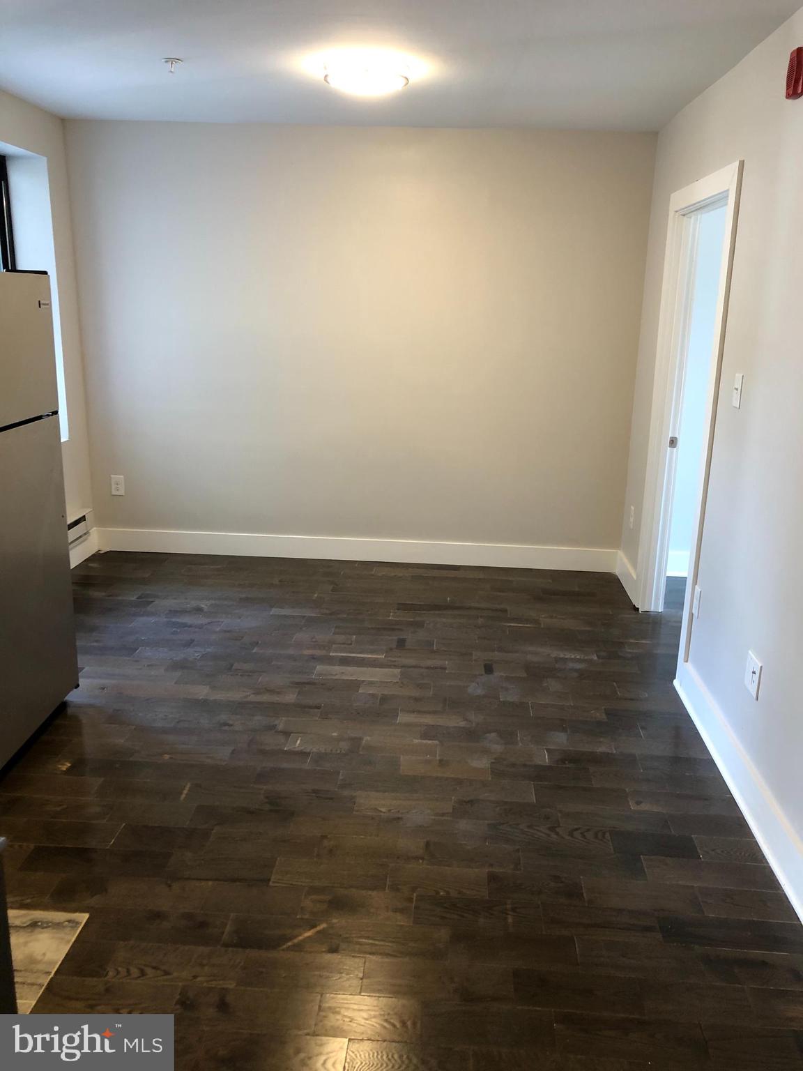 5101-7 North 12th Street, Unit 3C Philadelphia, PA 19141 - Photo 3 of 6 a view of an empty room with wooden floor and a window