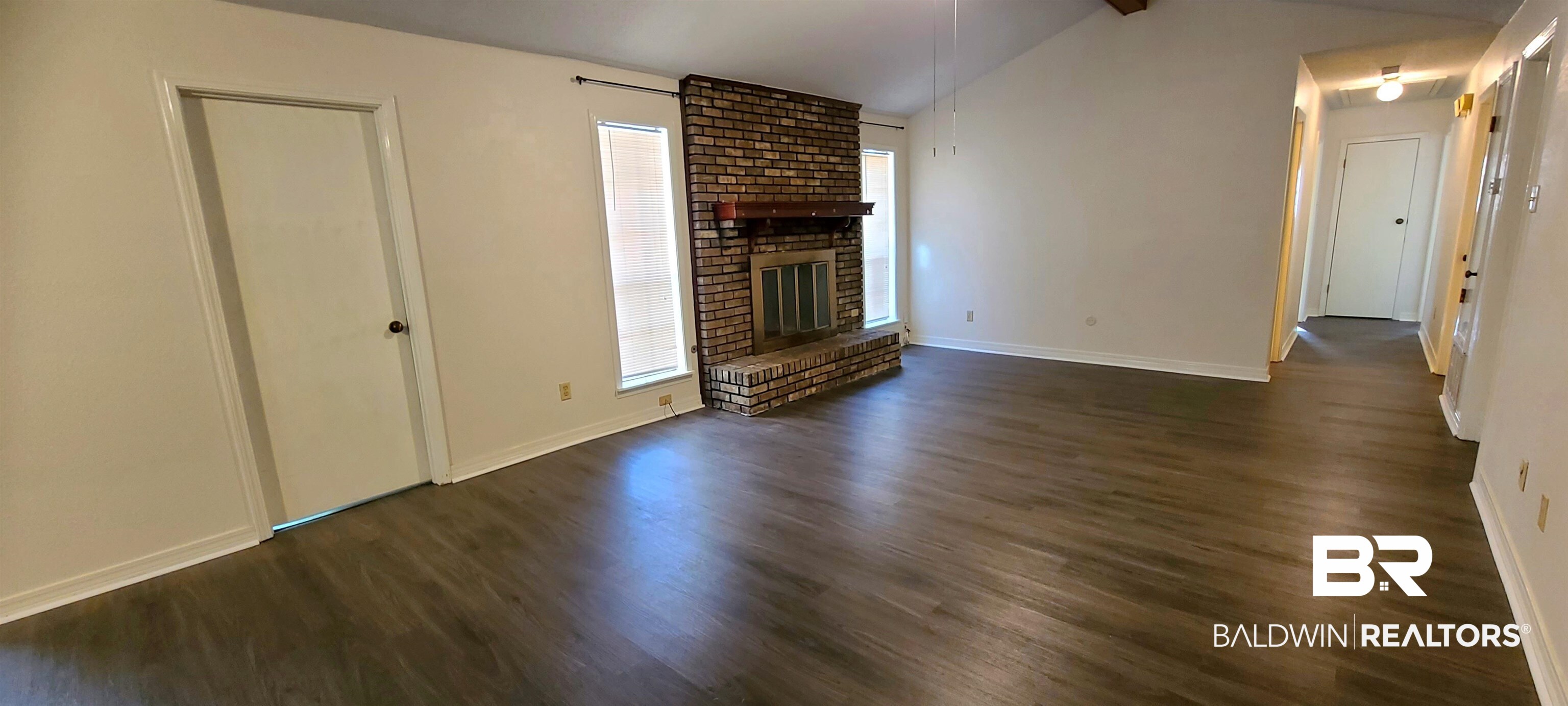 5305 Wilhelm Drive Mobile, AL 36618 - Photo 2 of 16 Unfurnished living room with dark wood-style floors, baseboards, lofted ceiling, plenty of natural light, and a brick fireplace