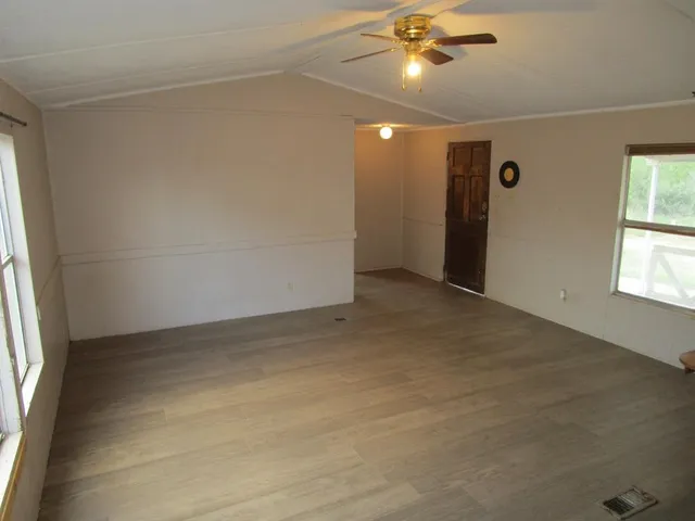 en empty room with windows and ceiling fan
