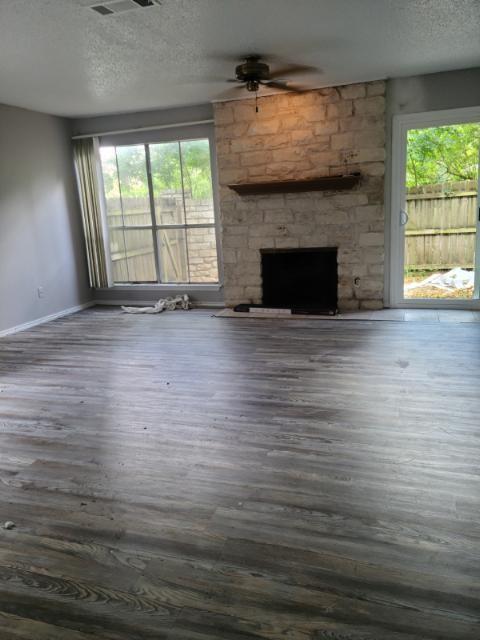 6900 Old Quarry Lane Austin, TX 78731 - Photo 2 of 9 Unfurnished living room featuring a fireplace, wood finished floors, a textured ceiling, and ceiling fan