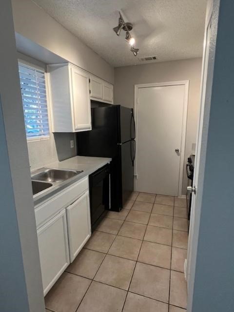 6900 Old Quarry Lane Austin, TX 78731 - Photo 4 of 9 Kitchen with white cabinets, light countertops, dishwasher, light tile patterned floors, and a textured ceiling