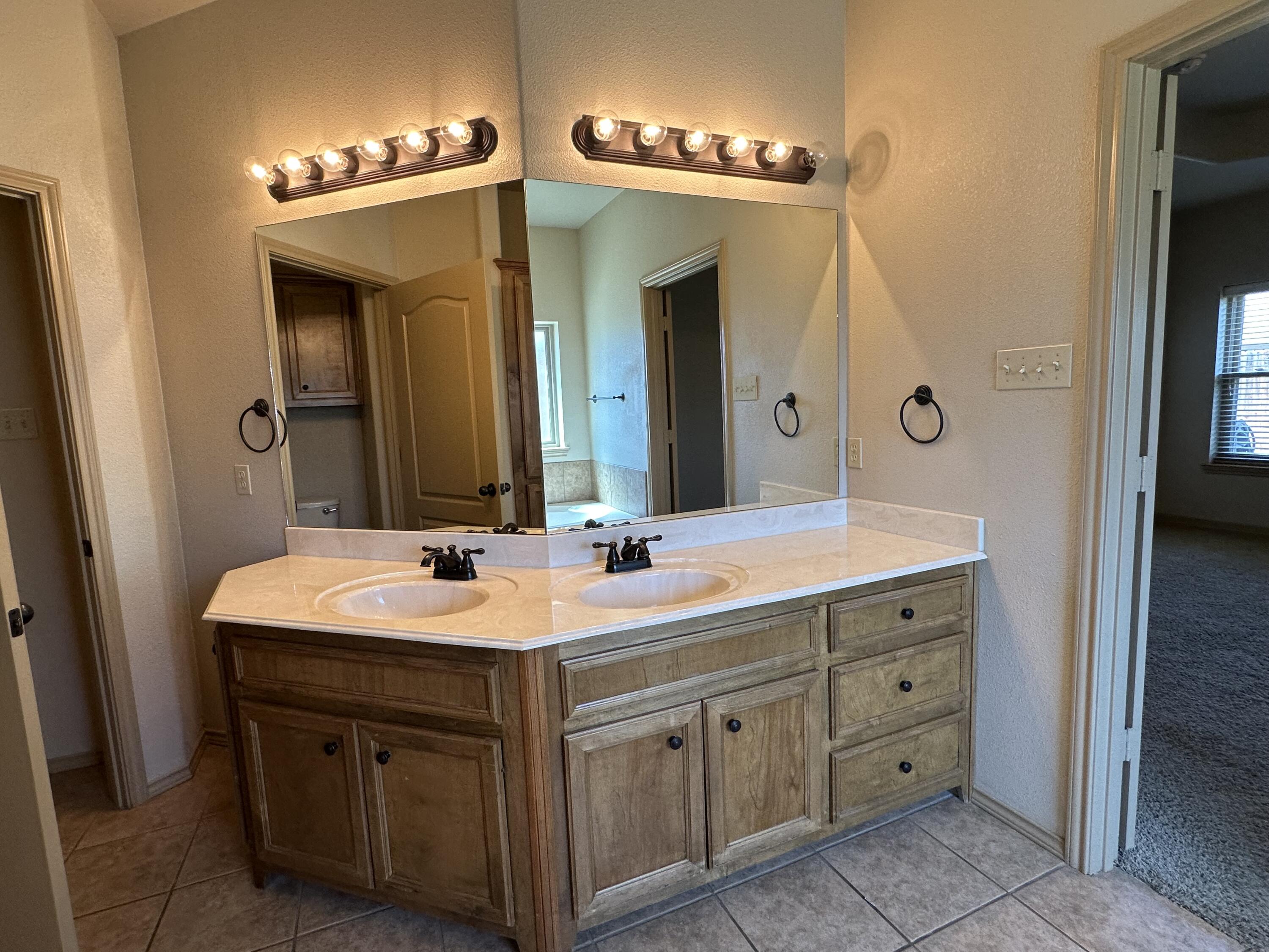 6114 75th Place Lubbock, TX 79424 - Photo 20 of 35 a bathroom with a double vanity sink and a mirror