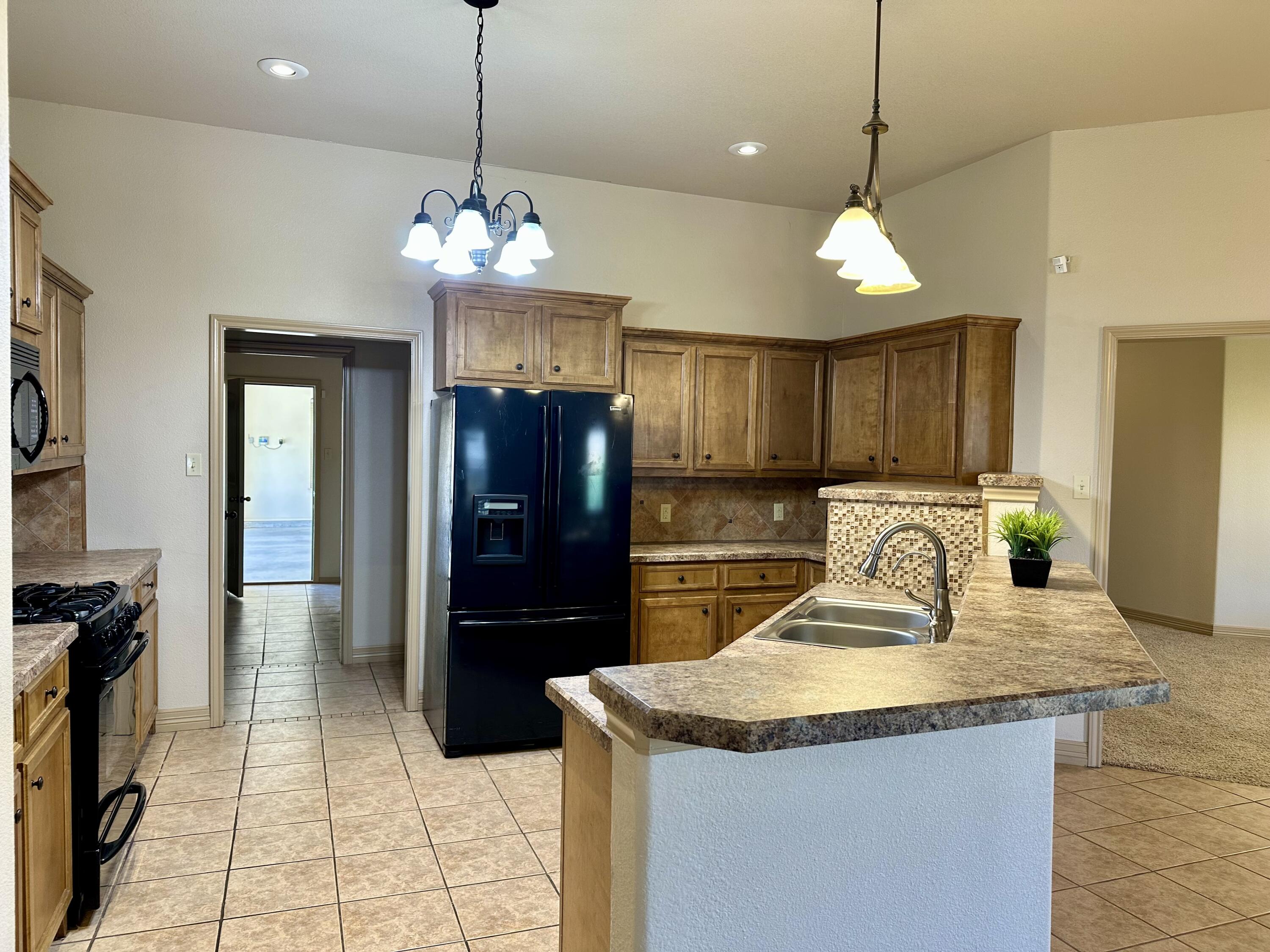 6114 75th Place Lubbock, TX 79424 - Photo 4 of 35 a kitchen with granite countertop stainless steel appliances a sink and a refrigerator