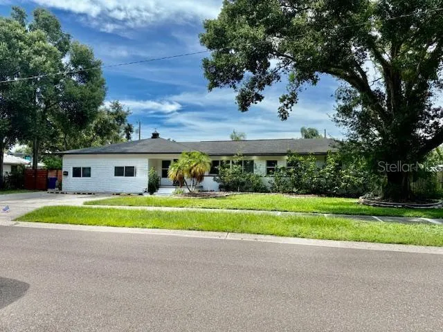 a view of a house with a big yard and large trees