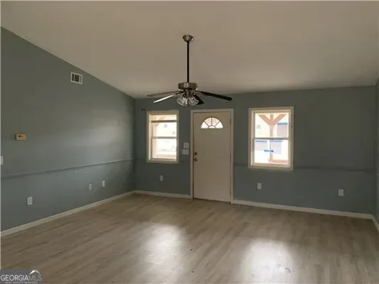 an empty room with wooden floor and windows