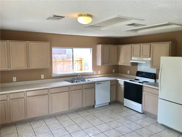a kitchen with cabinets appliances a sink and a window