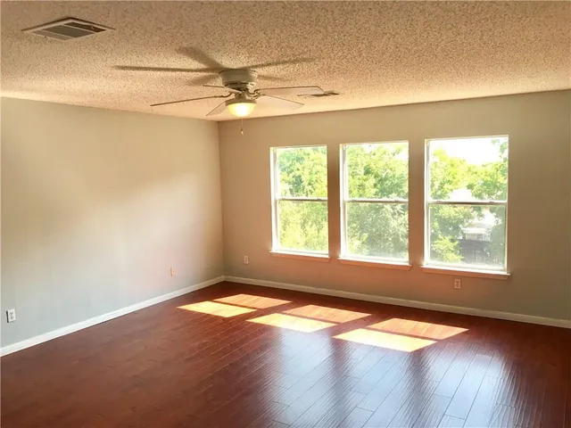 an empty room with wooden floor and windows