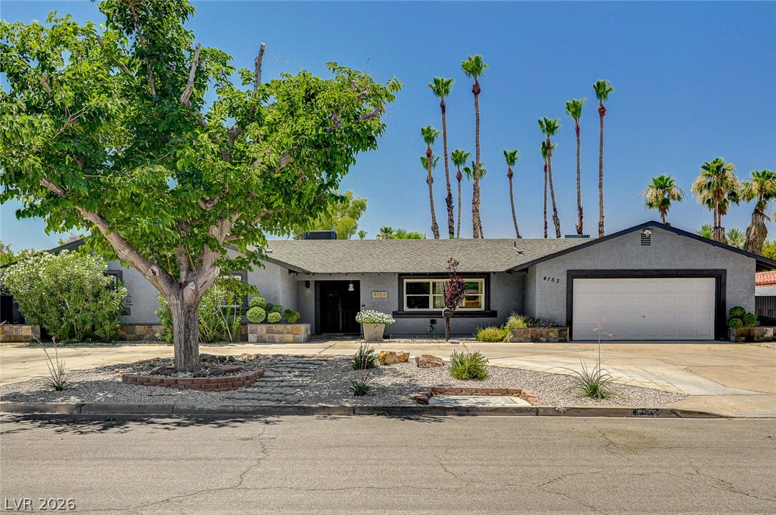 4153 Woodcrest Road Las Vegas, NV 89121 - Photo 3 of 58 Mature trees and desert landscaping frame this inviting single-story residence with a two-car garage.