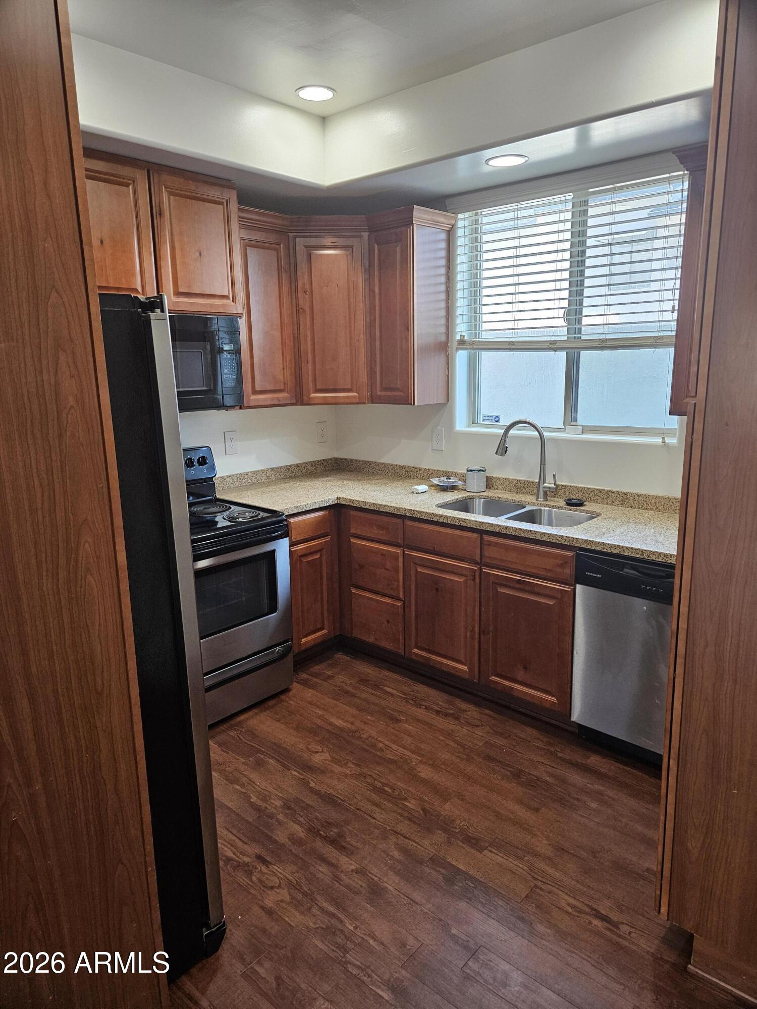 4113 North 22nd Street, Unit 5 Phoenix, AZ 85016 - Photo 5 of 60 a kitchen with stainless steel appliances granite countertop wooden cabinets a sink a stove a refrigerator with wooden floor and cabinets