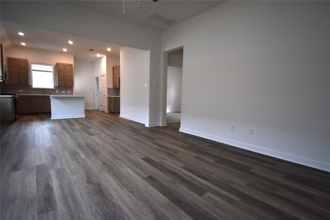 18113 Emu Lane Manor, TX 78653 - Photo 2 of 20 an empty room with wooden floor and a kitchen