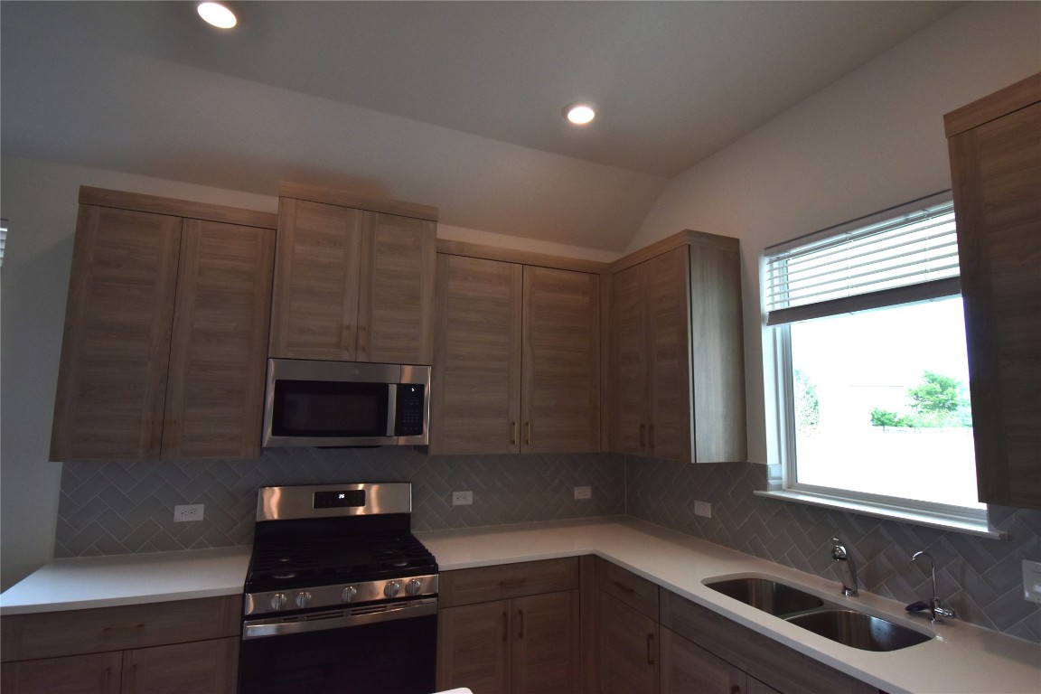 18113 Emu Lane Manor, TX 78653 - Photo 3 of 20 a kitchen with a sink a microwave a window and cabinets