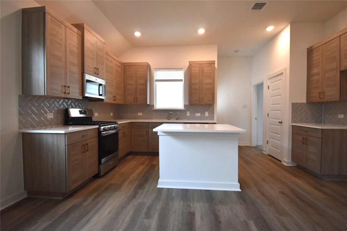 18113 Emu Lane Manor, TX 78653 - Photo 4 of 20 a kitchen with stainless steel appliances granite countertop a sink a stove a refrigerator cabinets and wooden floor