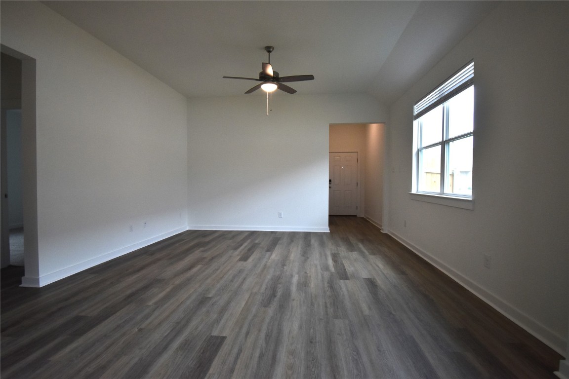 18113 Emu Lane Manor, TX 78653 - Photo 6 of 20 an empty room with wooden floor chandelier fan and windows