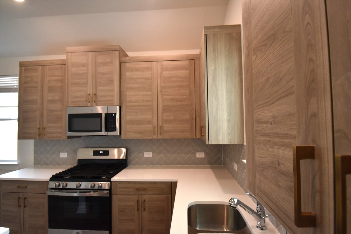 18113 Emu Lane Manor, TX 78653 - Photo 8 of 20 a kitchen with granite countertop a sink a stove and cabinets