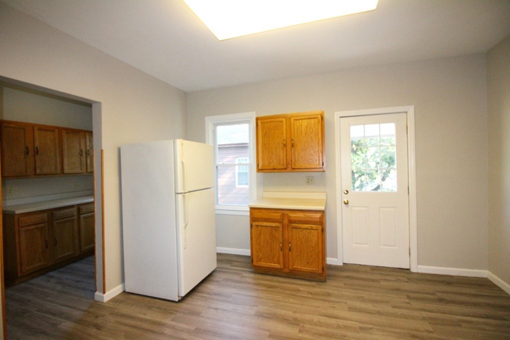 524 Armory Street Springfield, MA 01104 - Photo 3 of 11 an empty room with wooden floor cabinet and a kitchen space