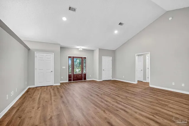 an empty room with wooden floor chandelier fan and windows