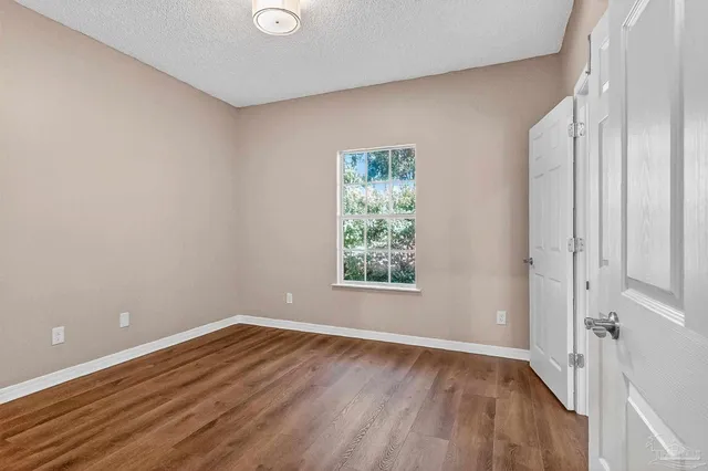 an empty room with wooden floor & windows