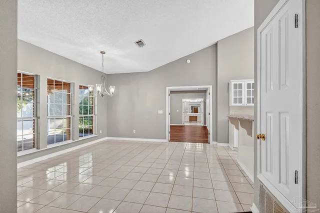 a view of an empty room with window and chandelier fan