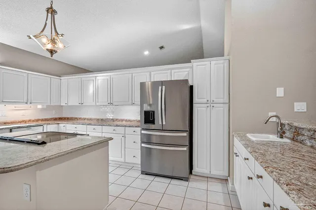 a kitchen with granite countertop white cabinets and white appliances