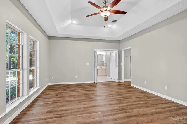 a view of an empty room with a window and wooden floor