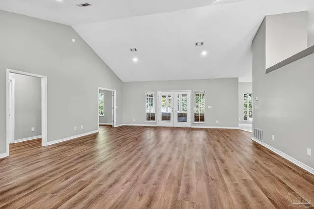 a view of an empty room with wooden floor and window