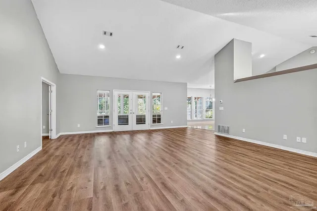 a view of an empty room with window and wooden floor