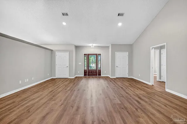 a view of an empty room with wooden floor and window