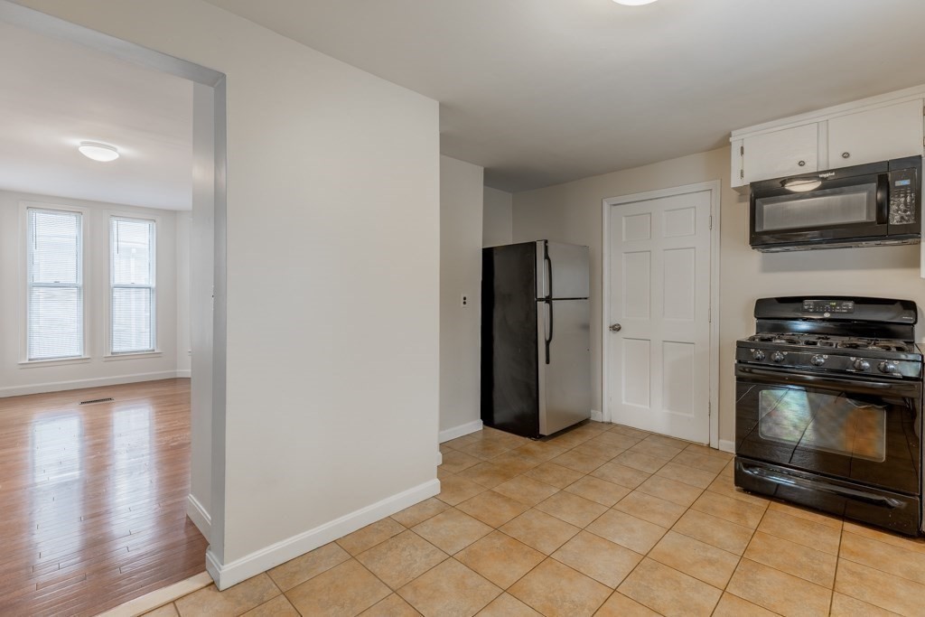 55 Morse Street, Unit 1 Watertown, MA 02472 - Photo 6 of 12 a kitchen with stainless steel appliances a stove a microwave and a refrigerator