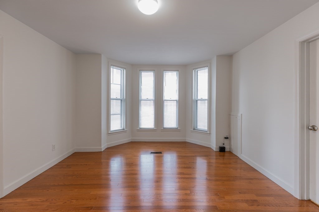 55 Morse Street, Unit 1 Watertown, MA 02472 - Photo 8 of 12 an empty room with wooden floor and windows