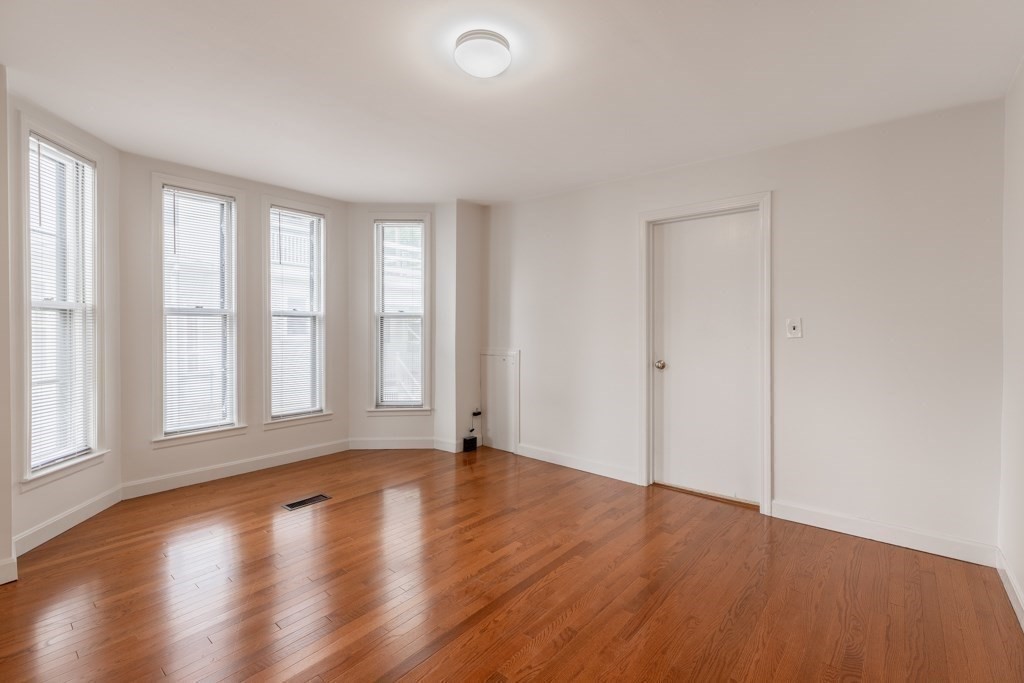 55 Morse Street, Unit 1 Watertown, MA 02472 - Photo 9 of 12 an empty room with wooden floor and windows