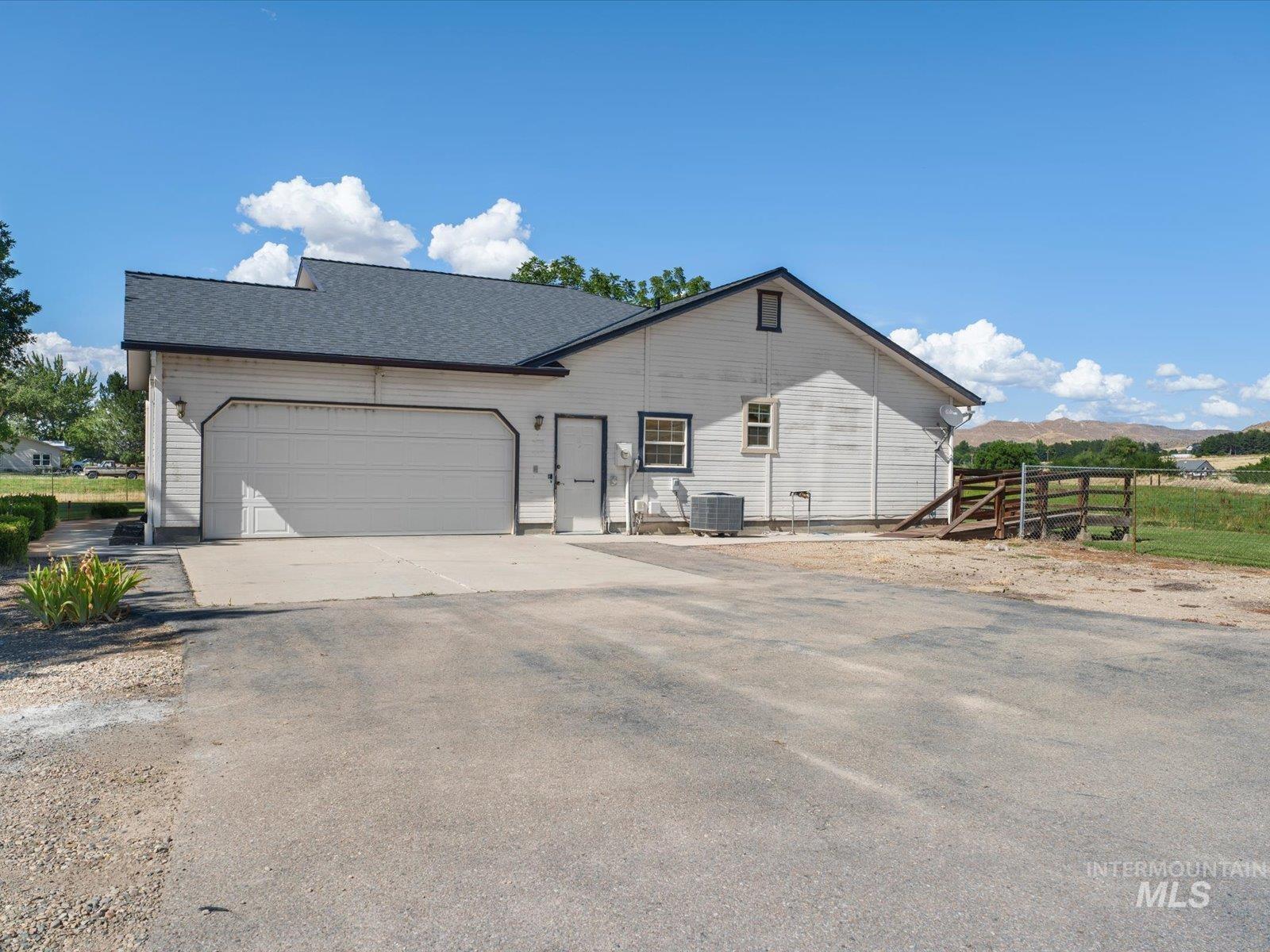 3540 Wills Road Emmett, ID 83617 - Photo 26 of 36 Exterior featuring a two-car garage, white siding, dark shingle roof, and a gravel driveway