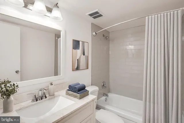 a bathroom with a bathtub shower sink vanity and toilet