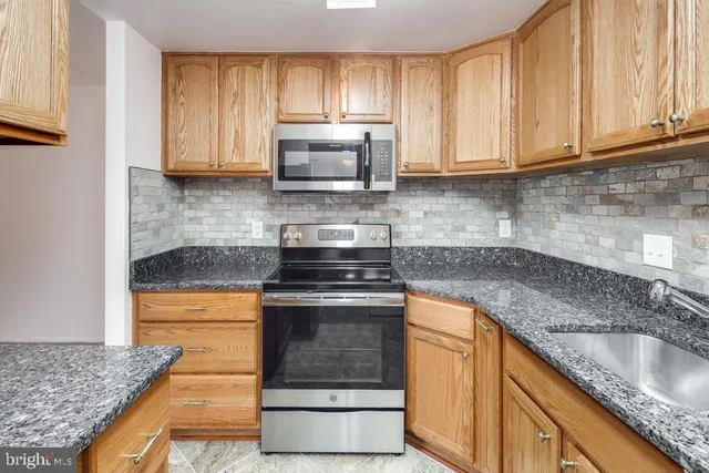a kitchen with granite countertop a sink stove and cabinets