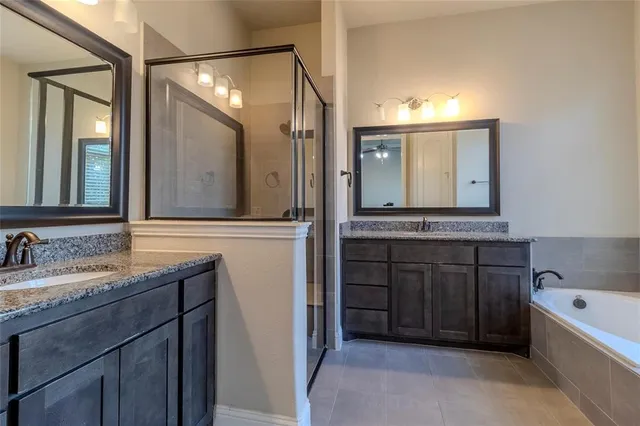 a bathroom with a tub a double vanity sink and mirror