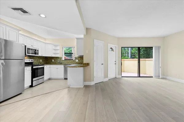 a kitchen with granite countertop white cabinets and stainless steel appliances