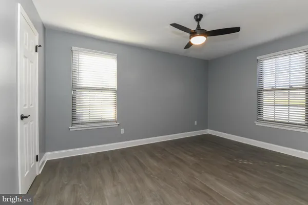an empty room with wooden floor ceiling fan and window
