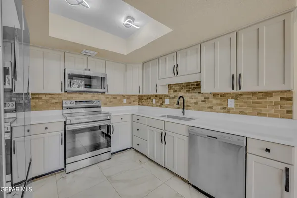 a kitchen with white cabinets sink and stainless steel appliances