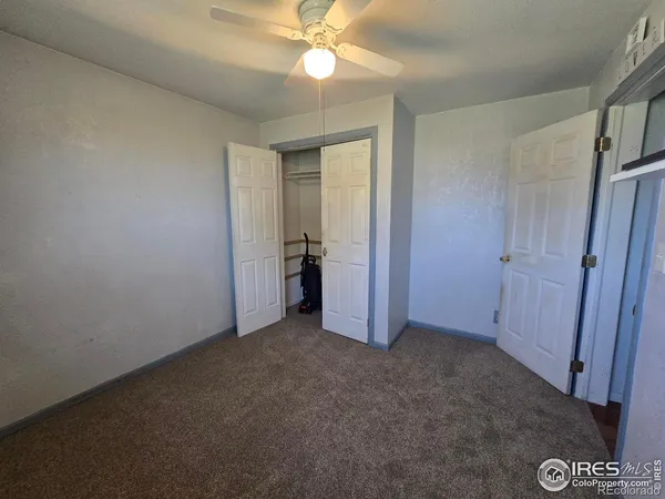 an empty room with closet and a chandelier fan