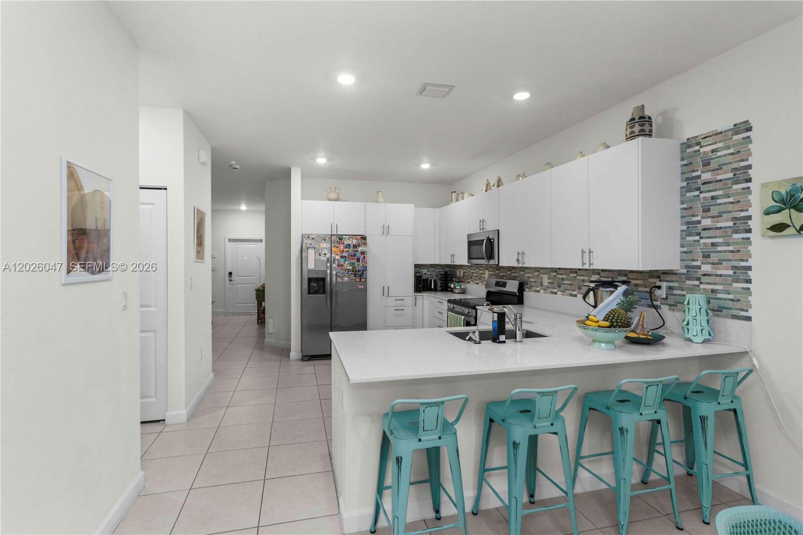 12862 Southwest 231st Street Miami, FL 33170 - Photo 12 of 30 a kitchen with stainless steel appliances kitchen island granite countertop a dining table chairs and a refrigerator