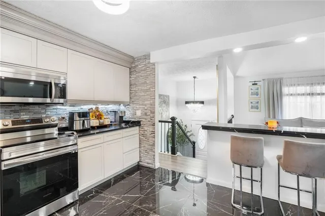 a kitchen with stainless steel appliances a stove a sink cabinets and a microwave