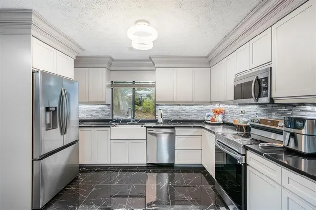 a kitchen with stainless steel appliances granite countertop a stove a sink dishwasher a refrigerator and a microwave