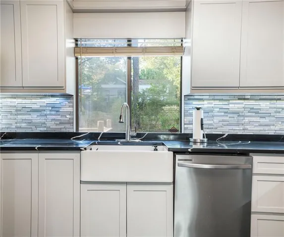 a kitchen with granite countertop a sink and a white wooden cabinets