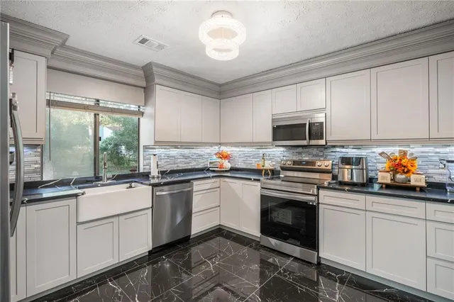 a kitchen with granite countertop white cabinets stainless steel appliances and a sink