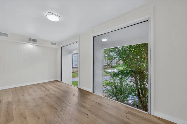 a view of empty room with wooden floor and fan