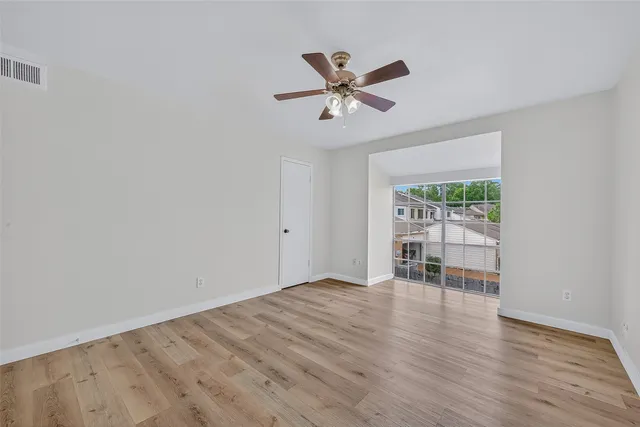 a view of empty room with wooden floor and fan