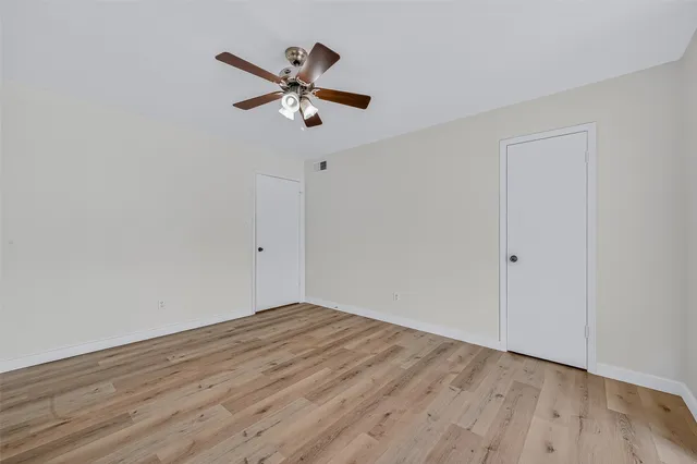a view of a room with wooden floor and a ceiling fan