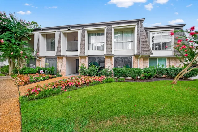 a front view of house and yard with beautiful flowers and green space