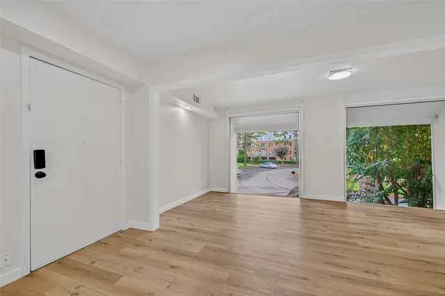a view of an empty room with a window and wooden floor