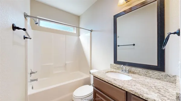 a bathroom with a granite countertop sink toilet and shower