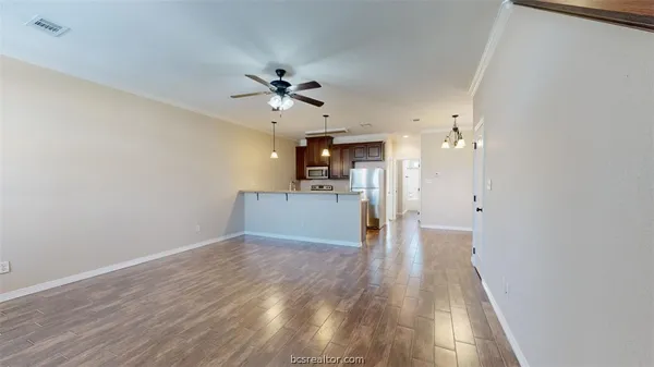 a view of a big room with wooden floor and a kitchen